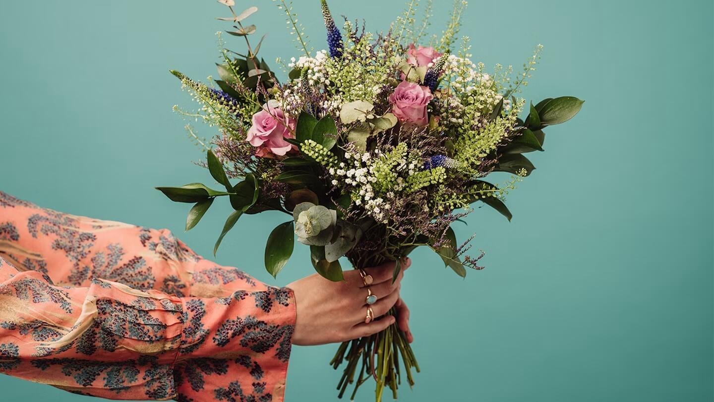 A close up of a hand holding some flowers